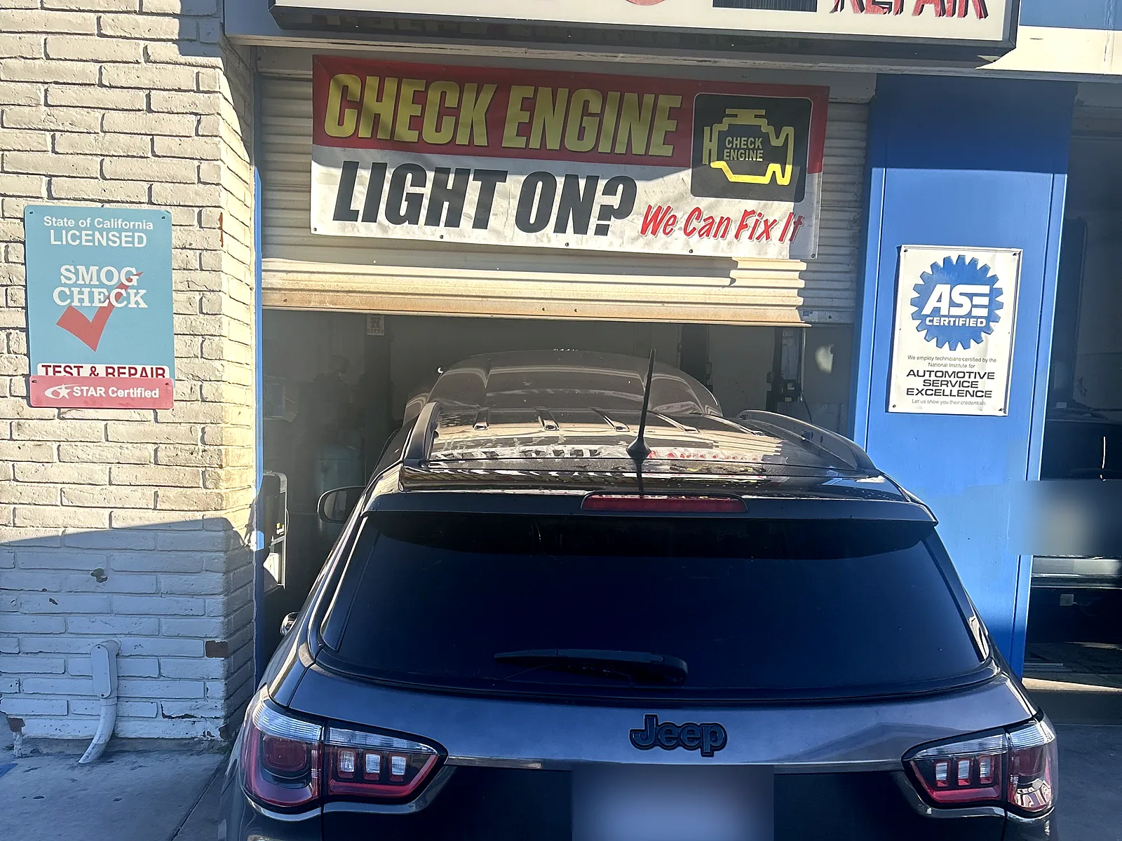 STAR smog check in Encinitas, CA: our shop front on Encinitas Blvd with the Smog / Auto Repair sign and a Jeep at the bay door